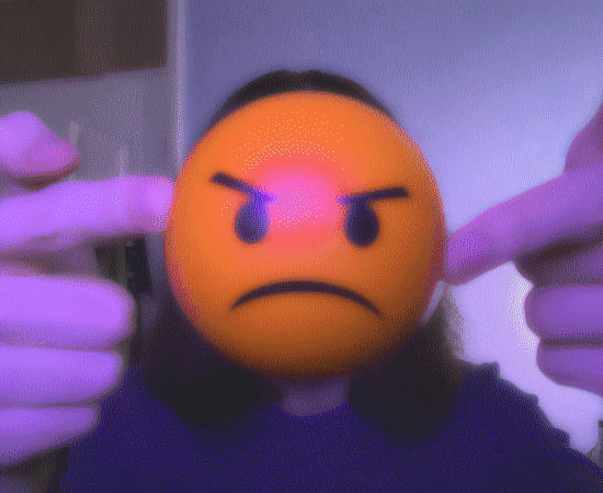 An image of me, I am holding up an orange stress ball and the perpsective of the camera makes this object obscure my face.